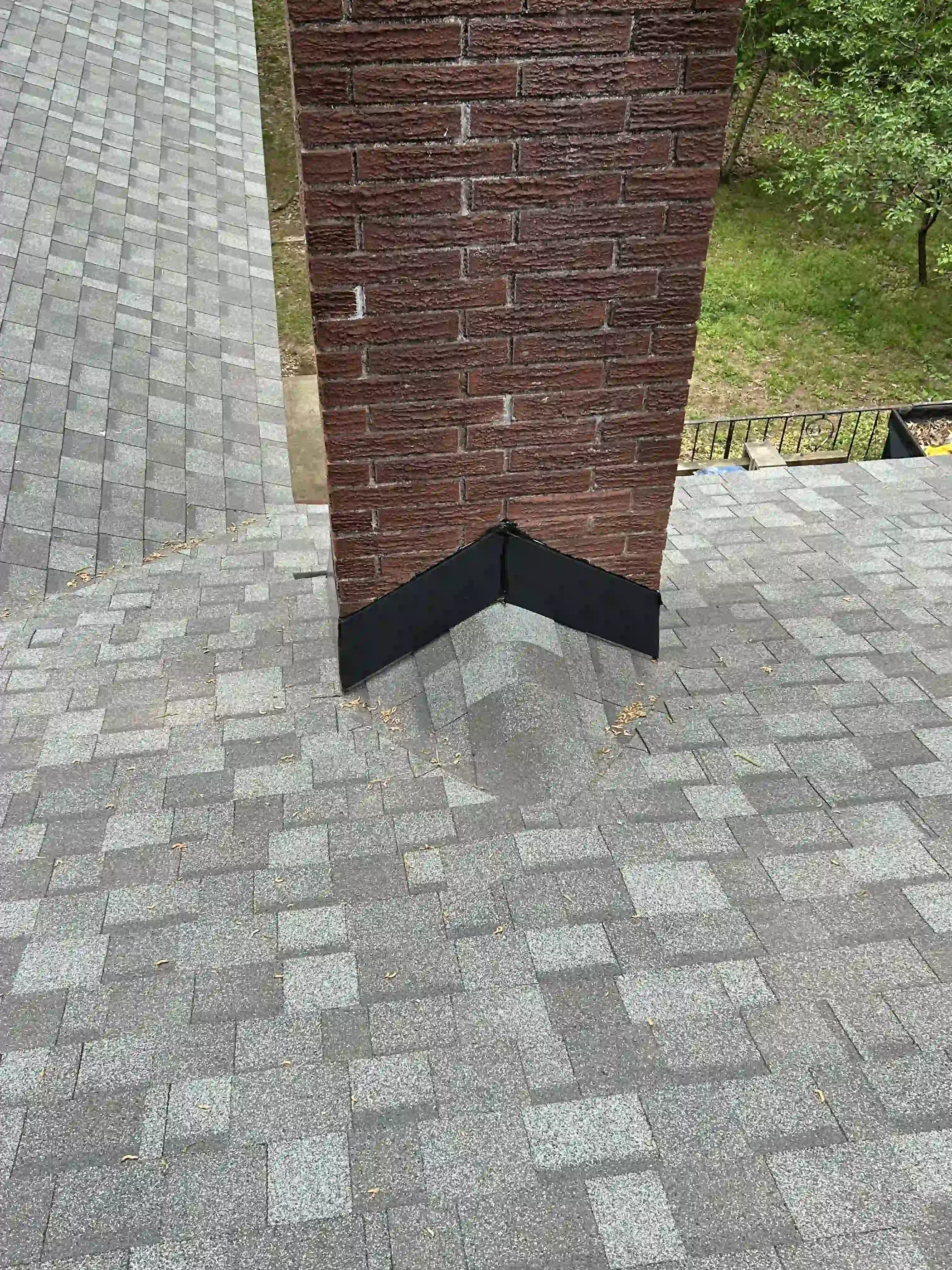 Close-up of chimney flashing where the metal meets the shingle course, a common early leak point