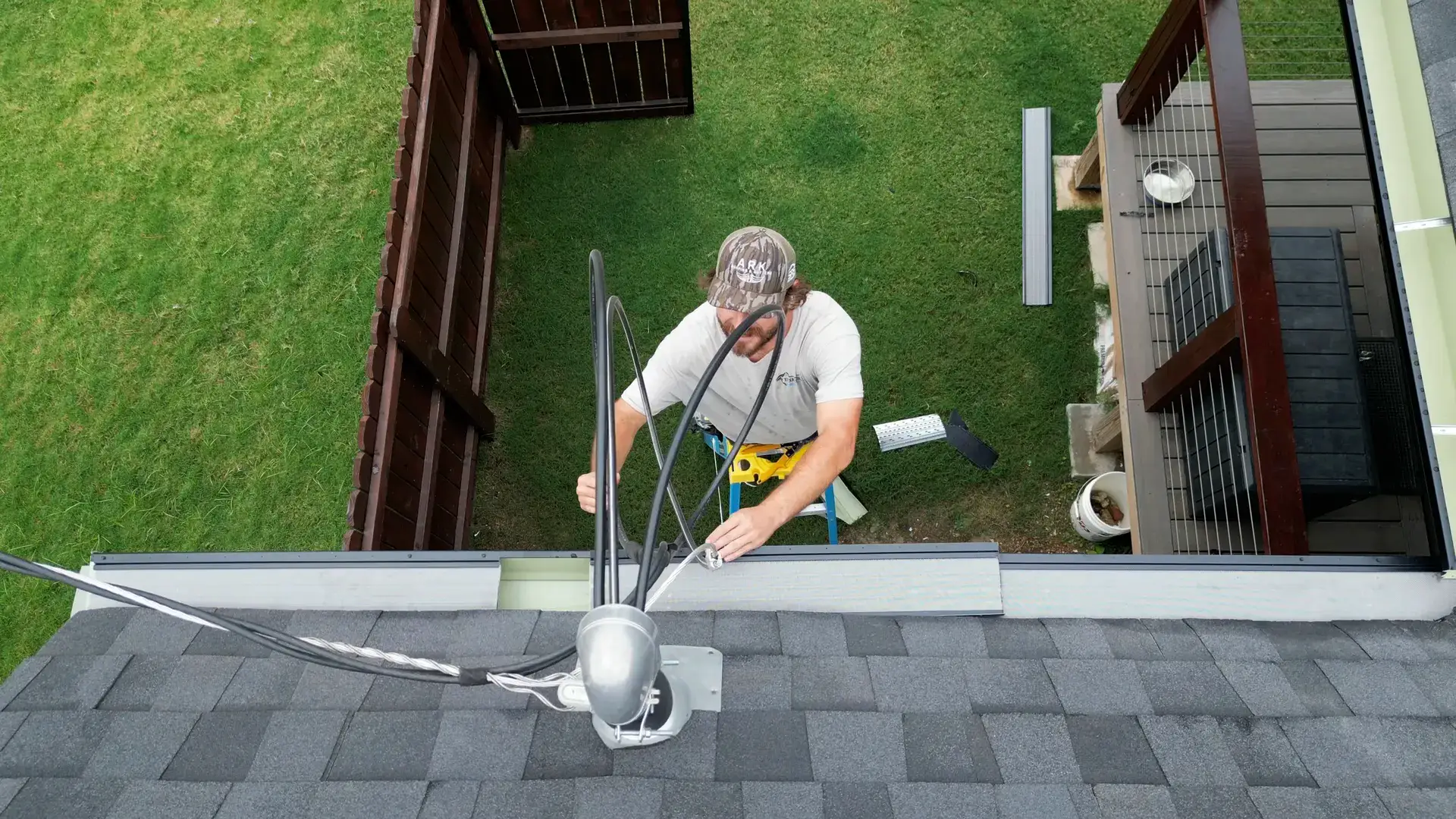 Technician lifting and resetting a gutter guard section along the shingle edge of a roof