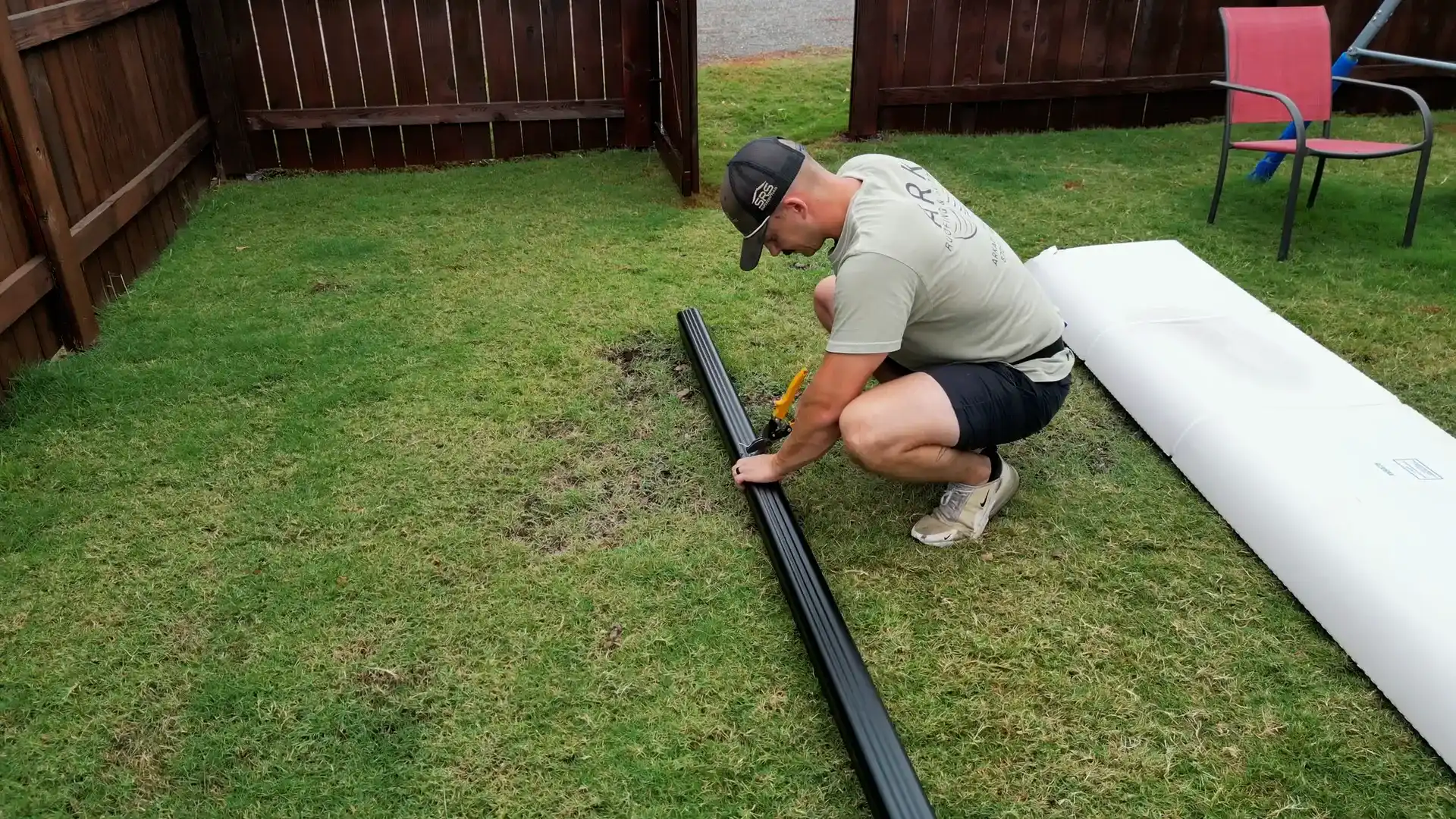 Ark Roofing owner trimming one continuous black seamless gutter length cut to size on site