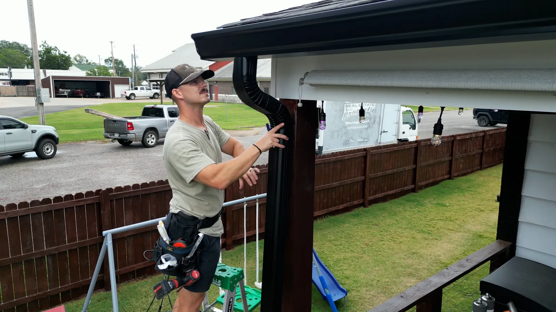Insured technician checking water flow at the base of a downspout after clearing the line