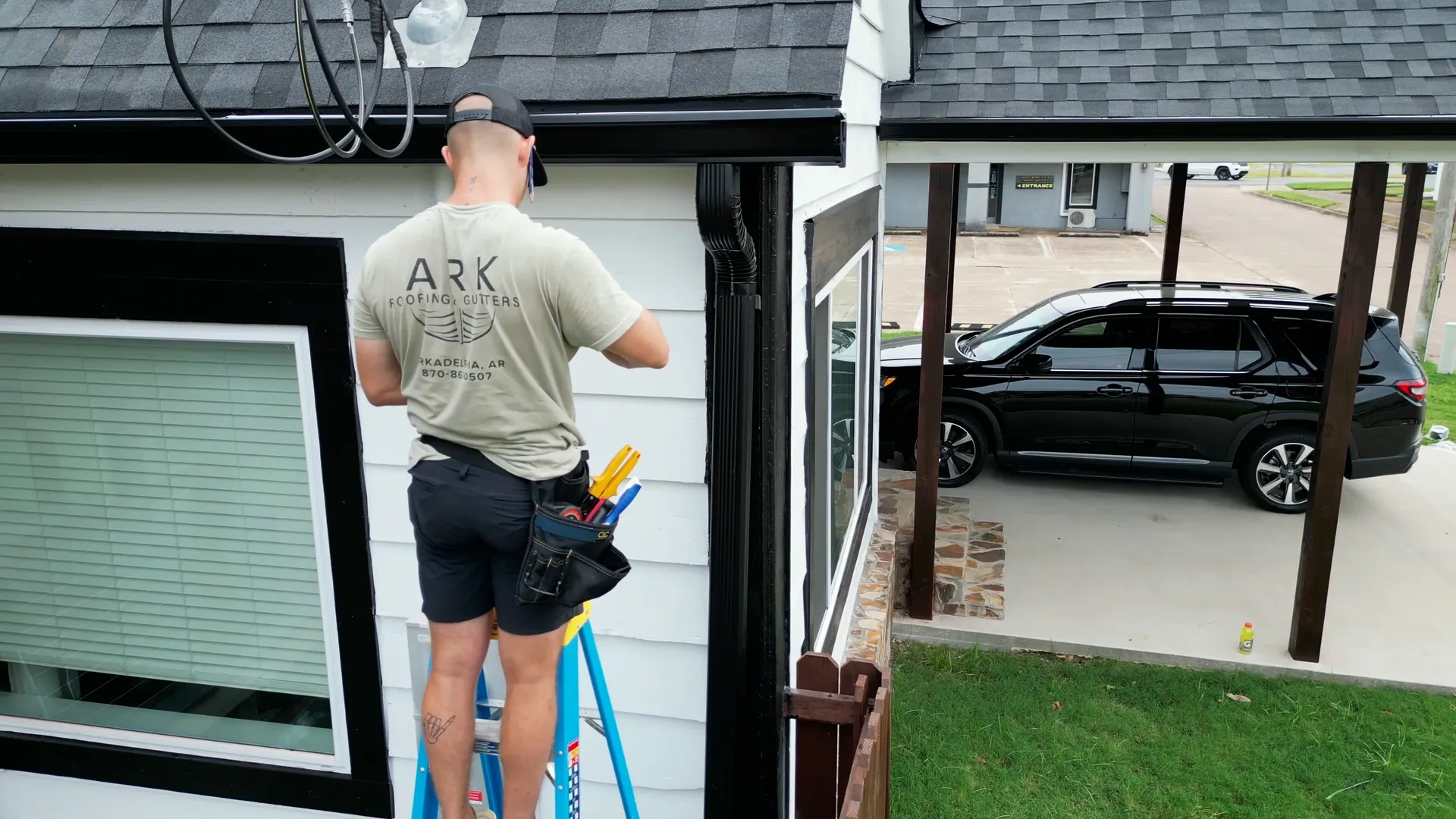 Ark Roofing crew member working safely from a ladder instead of a homeowner on a two-story roof