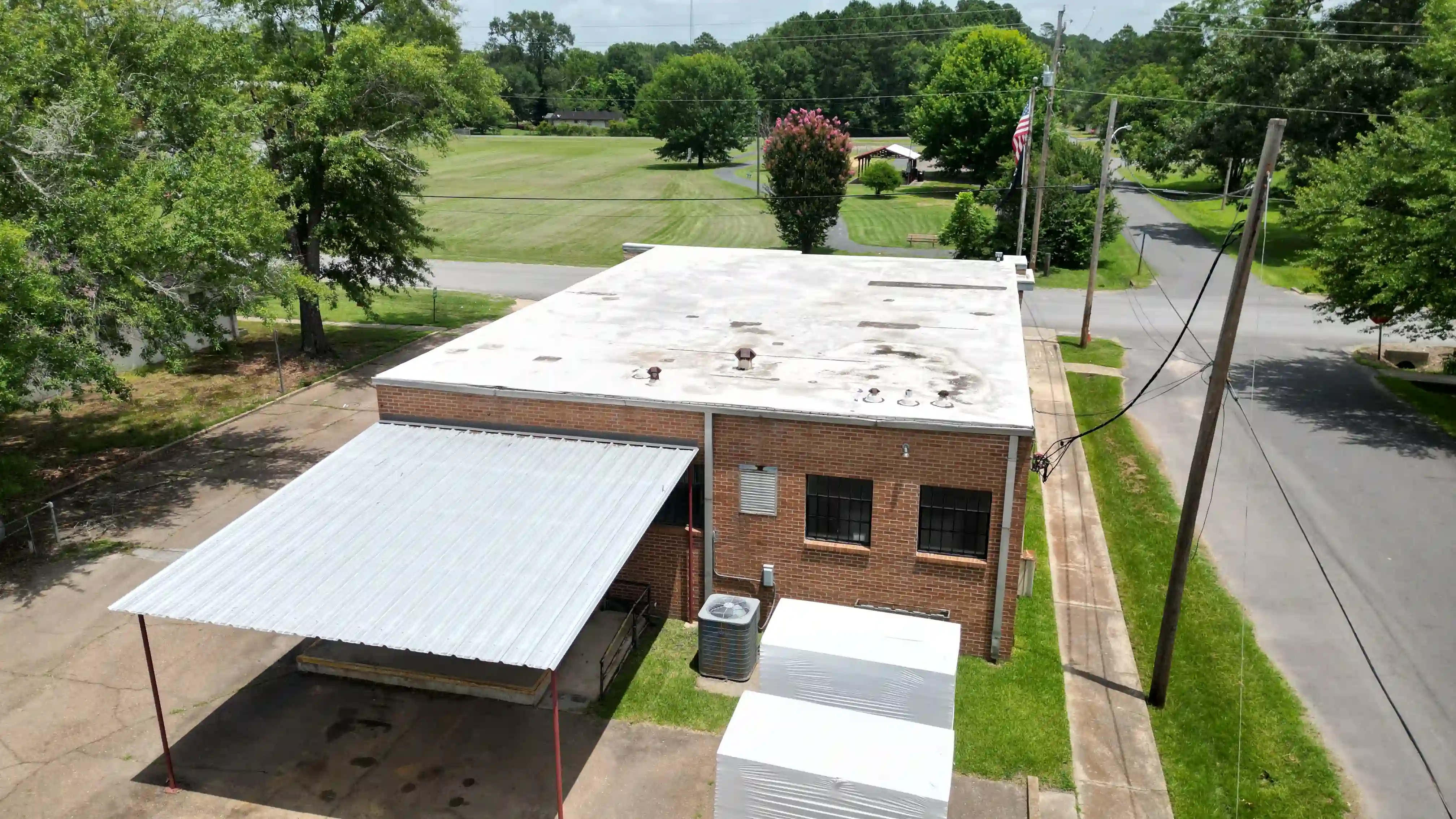 Aging flat commercial roof on a brick building, stained and patched before tear-off