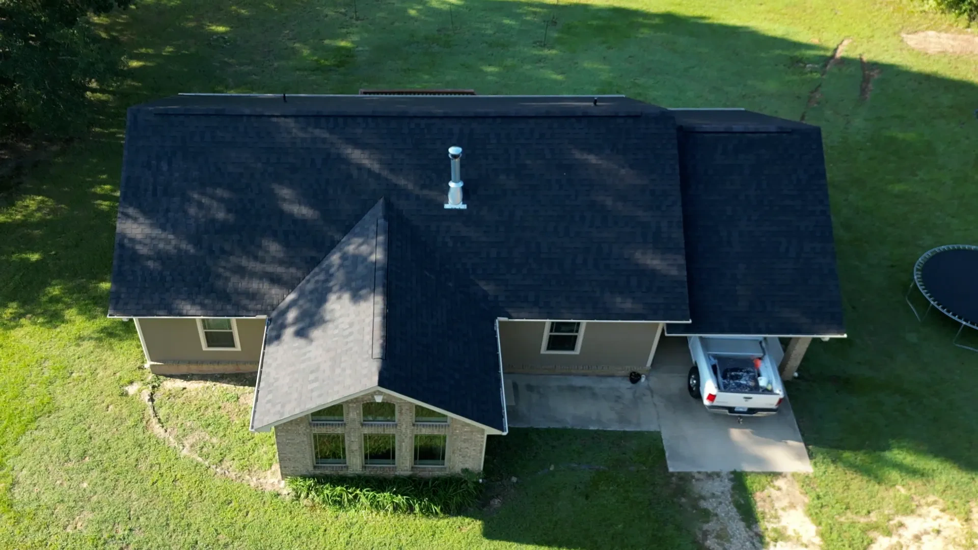 Crisp new dark shingle roof finished from ridge cap to eave on a newer brick home