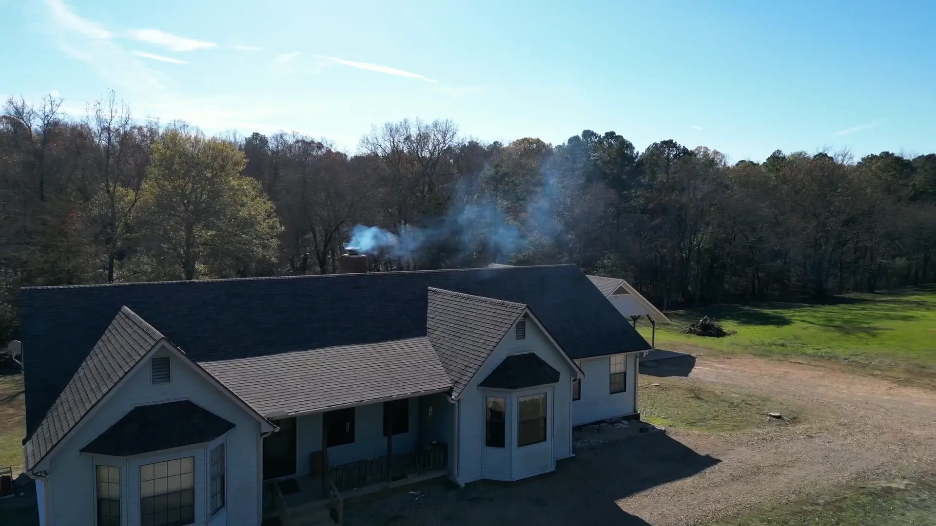 Older white farmhouse with a brand new dark shingle roof on a winter day