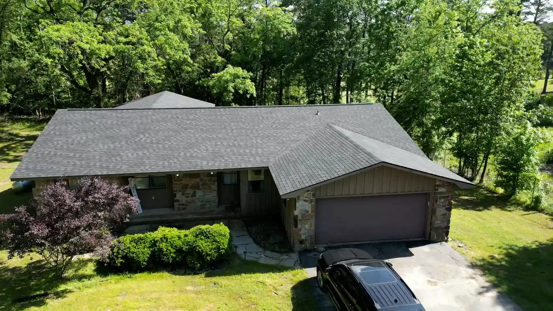 Crew working on a residential roof installation on a wooded lot
