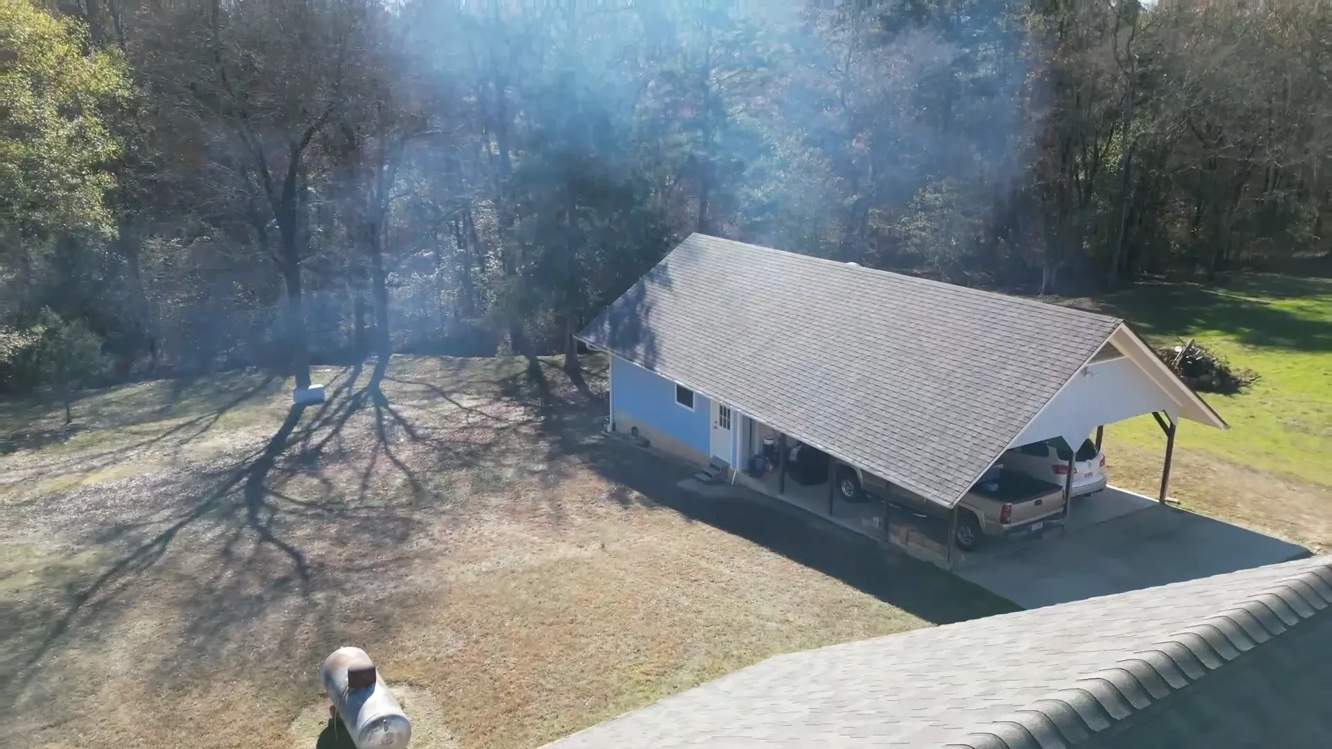 Small older valley house with weathered, aging shingles over its carport and main roof