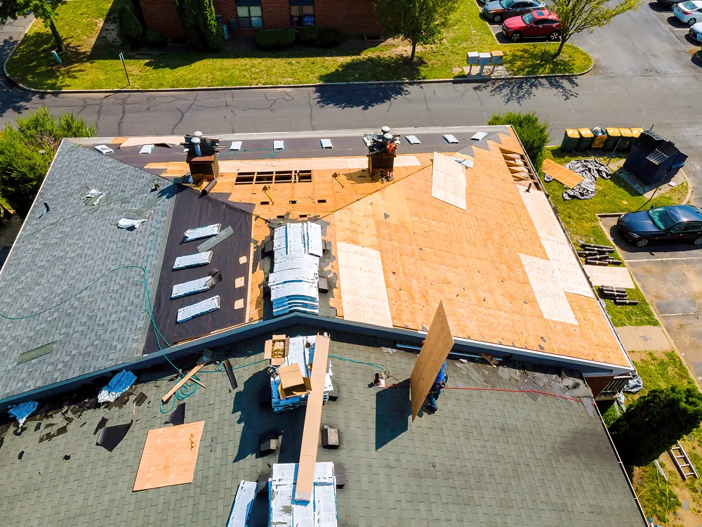 Aerial view of a commercial roof stripped to the deck with new layers being laid over it